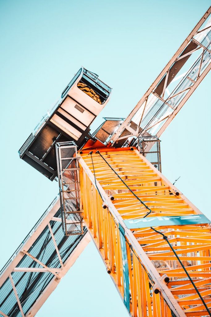pexels-photo-2068478 A striking low angle shot of a vibrant yellow tower crane against a clear sky, showcasing industrial power.